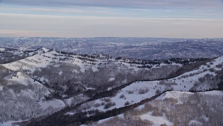 Aerial landscape over the mountains and peaks covered in snow under a morning sky