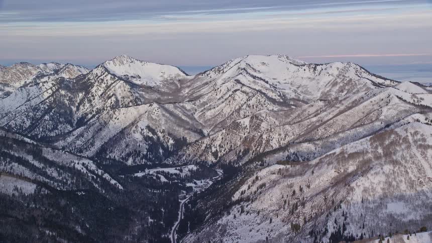 Panorama of peaks and snowcovered mountains with conifers under a dawn sky