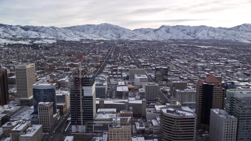 Aerial of an urban city during winter with frozen mountains in the background