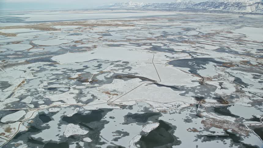 Aerial of a road in a landscape with a beach of frozen waters during winter