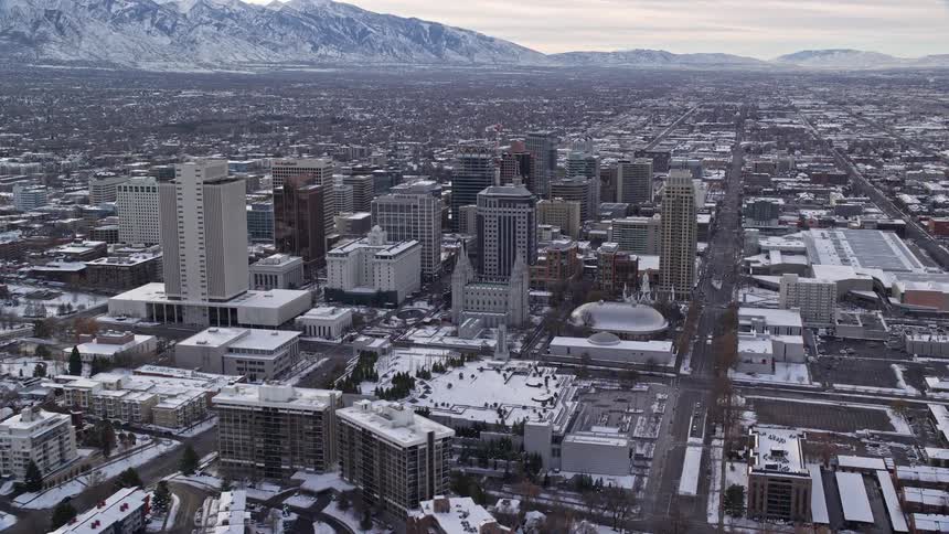 Panorama of a city with skyscrapers and residences covered in snow with mountains in the horizon