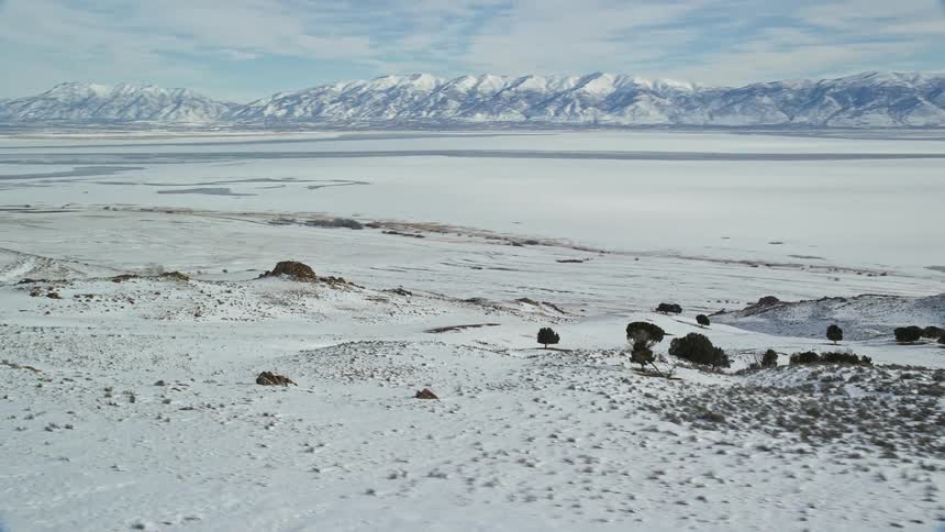 Snow covers mountain ranges and the plain between them on a cloudy winter day