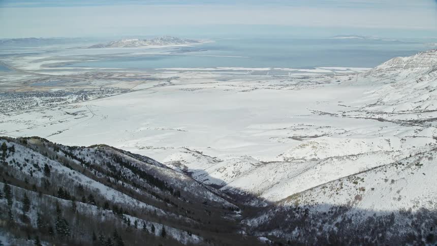 Aerial of a valley surrounded by frozen mountains and a beach during winter