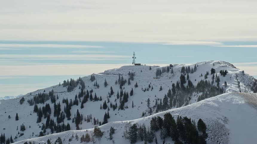 Panorama of a mountain with coniferous trees covered in snow overlooking the sky with clouds