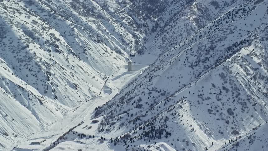 Aerial view of baltimore gulch with lone building in the oquirrh mountains with snow