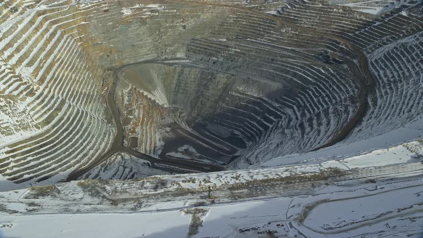 Panorama of a hole in the middle of a rock quarry covered in snow