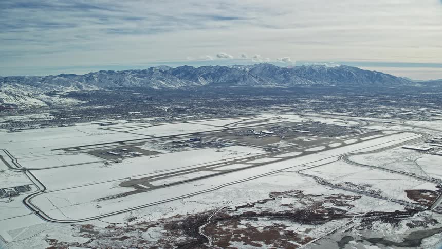Aerial view of an airport covered in snow next to the mountains