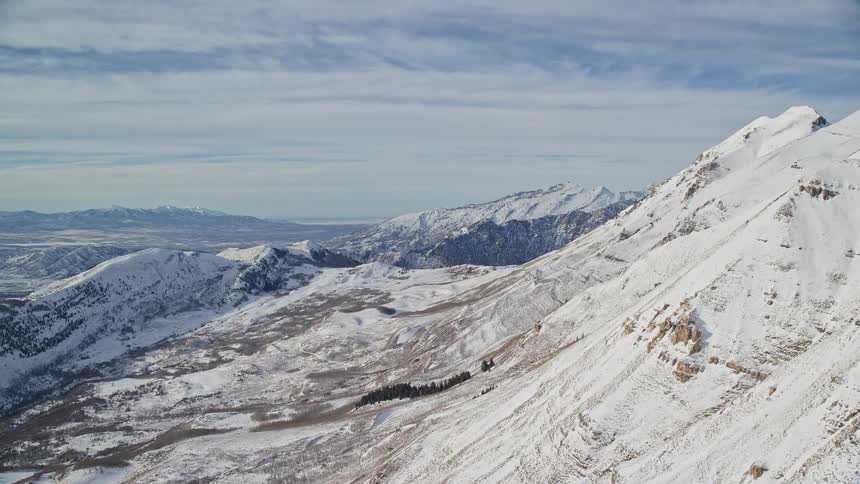 Snow covers the sloping side of a mountain within a large mountain range