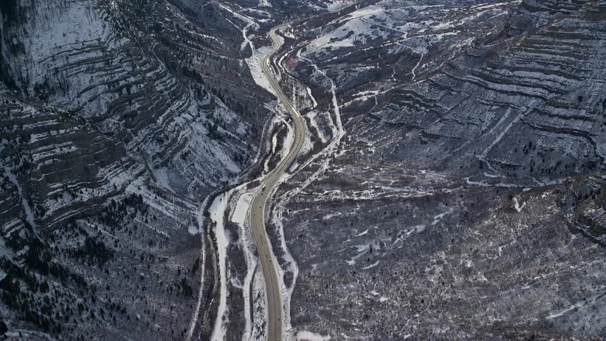 Aerial view of a central road amidst snowcovered mountains in daylight