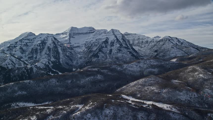Aerial panorama of a mountain range with cliffs covered in snow