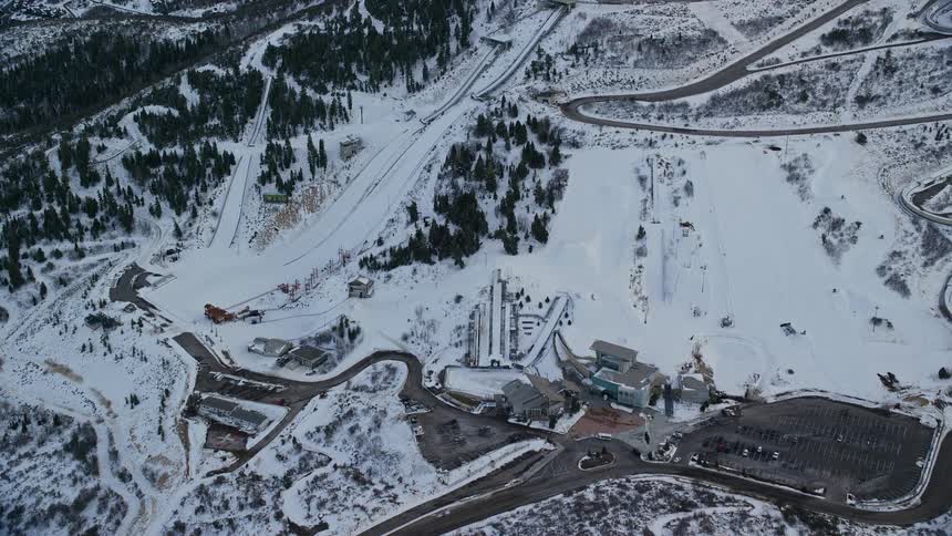 Aerial of a snowy ski slopes and a ski resort as the sun is almost down