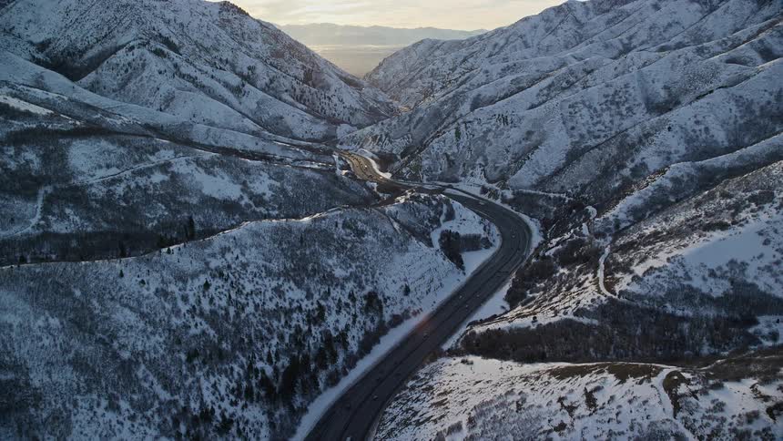 A large asphalt highway amidst snowy mountains