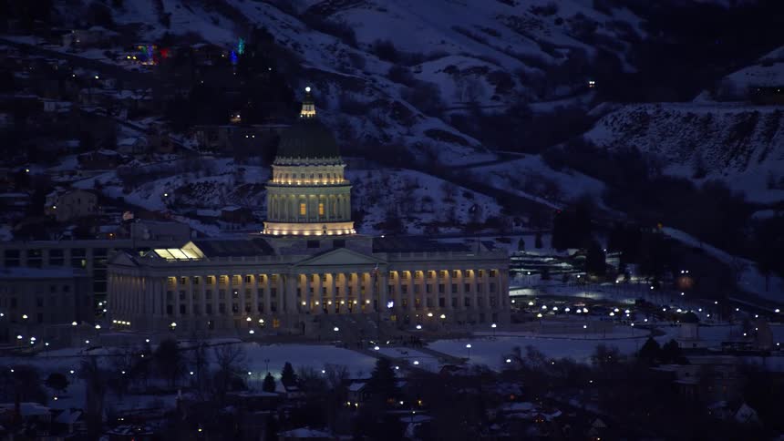 Aerial panorama of the illuminated congress building at night amidst mountains and snow