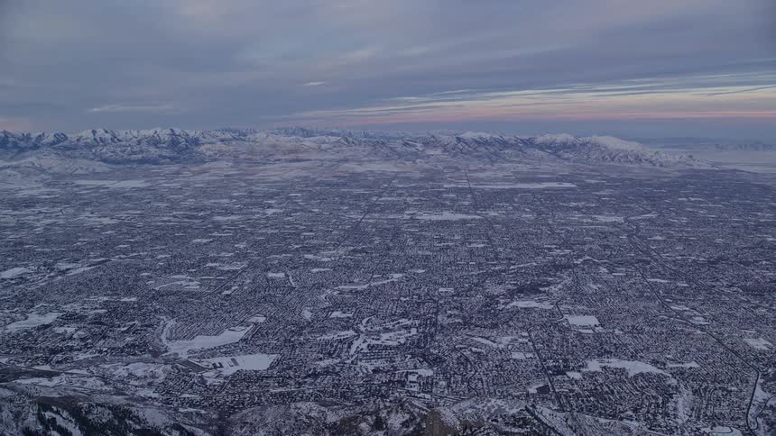 Aerial of an entire city under a hazy snow sky with mountains and purple sky on a dull winter day