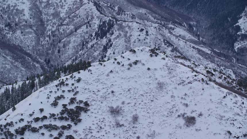An aerial perspective revealing a snowcovered mountain peak standing tall against a backdrop of serene wintry landscapes
