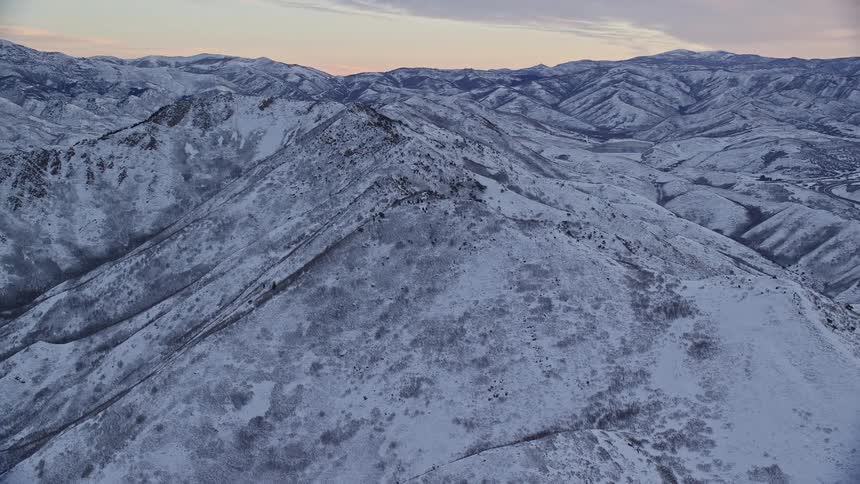 Aerial panorama of a mountain range covered in snow in the morning