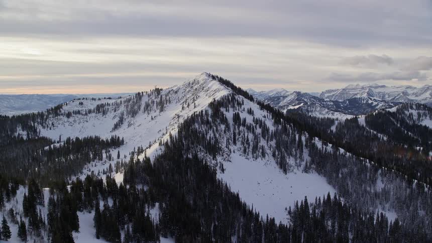 Aerial panorama of mountains and peaks with conifers covered in snow on a morning