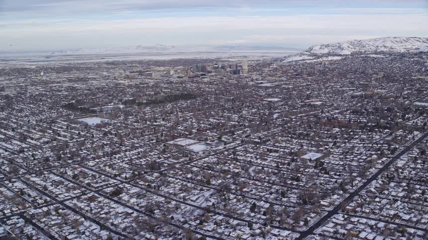 Aerial of snow covered residential neighborhoods bordering downtown and a mountain