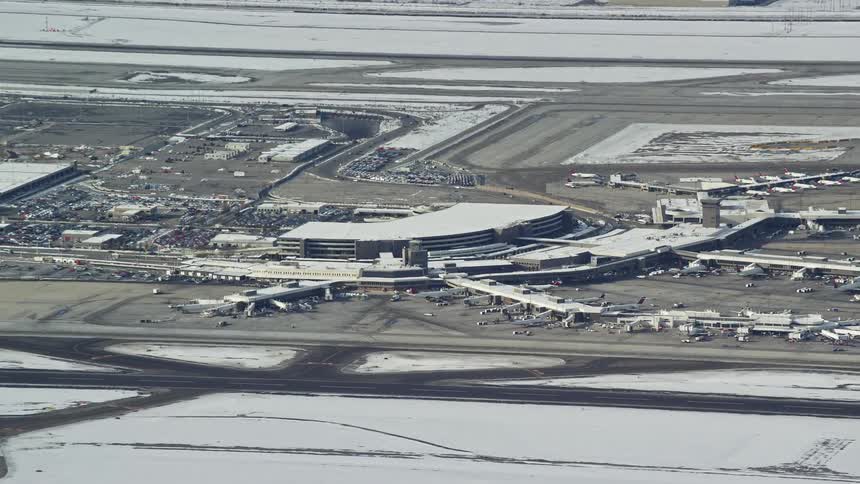 Snow covers the ground around a large airport on a sunny day