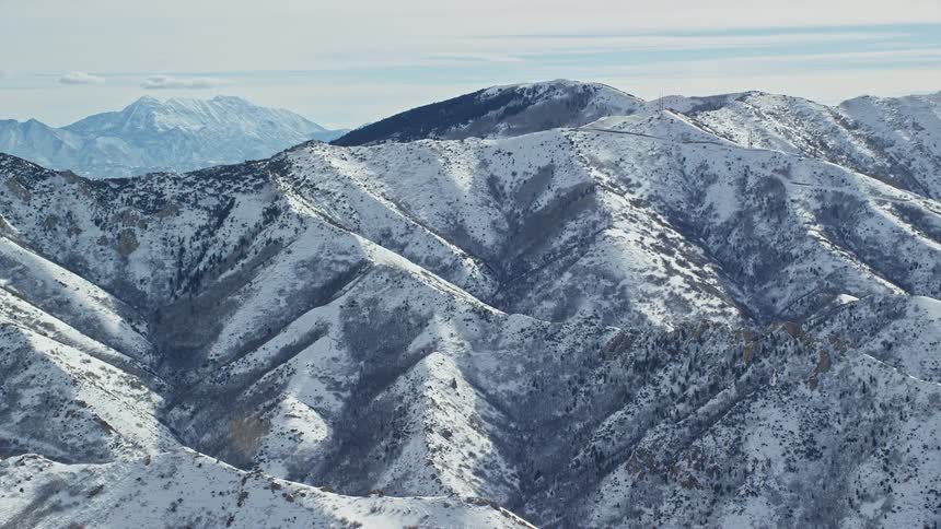 Snow covered mountains with mountains in the distance under a cloudy sky