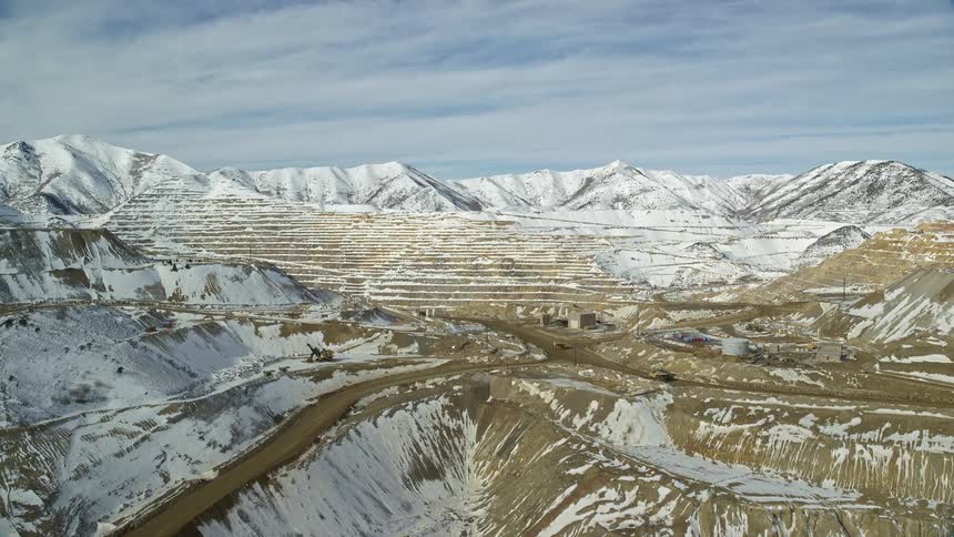 Trucks driving along a dirt road on top of a mountain during winter