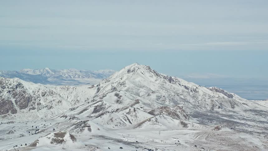 Snow covers mountainous landscape under an overcast sky