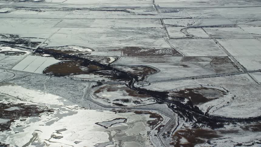 An aerial view of a ground covered in white snow and a part with something black