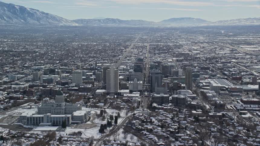 An aerial view of a large metropolitan city near some mountains in winter