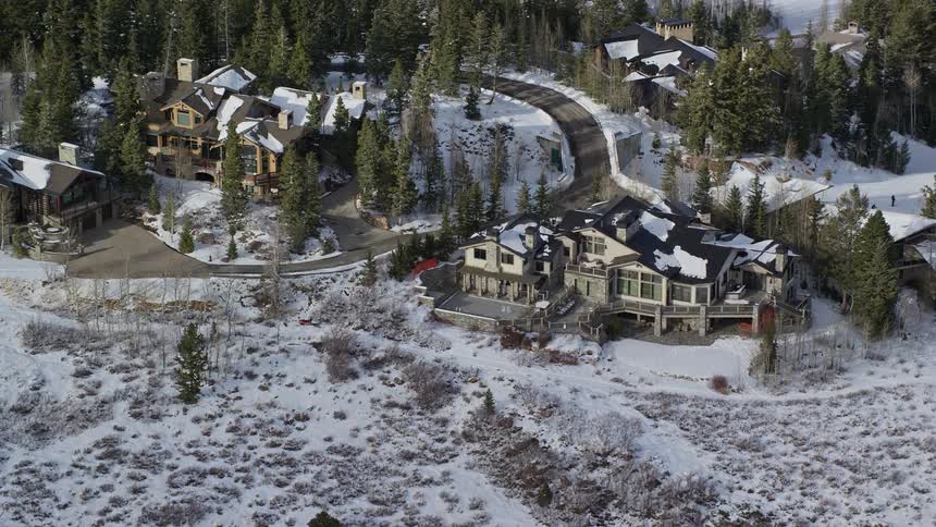 Several houses in a region with pine trees and lots of snow