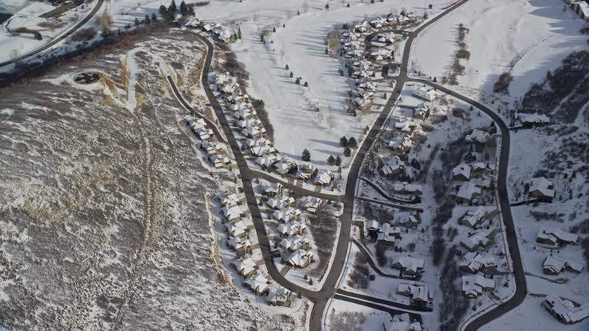 An aerial view of a small rural town with lots of snow on the ground and close to mountains