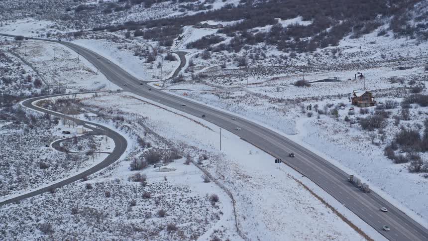 An aerial view of cars driving on a highway on the snowy field