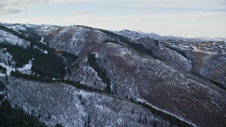 Aerial panorama of a mountain range and peaks with forests covered in snow