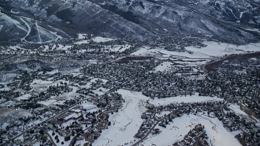 Aerial panorama of an urban city covered in snow and surrounded by a chain of mountains
