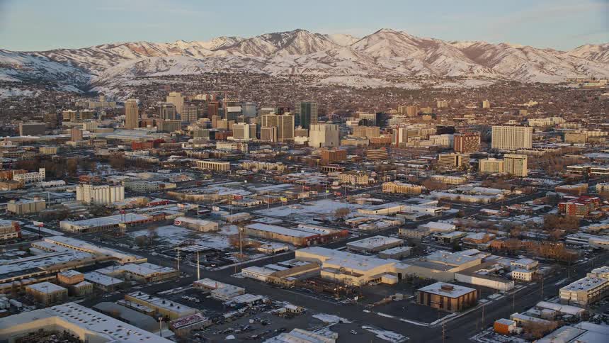 Aerial view of a large city with a backdrop of snowcovered mountain range