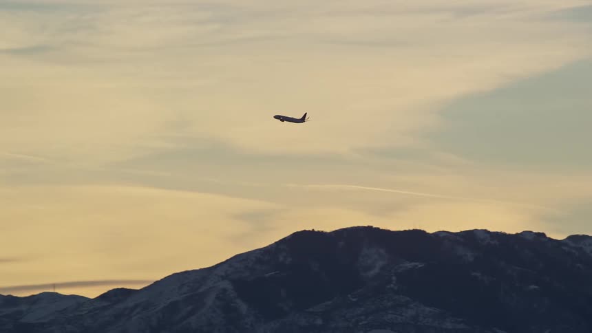 An airplane takes off and flies over mountains