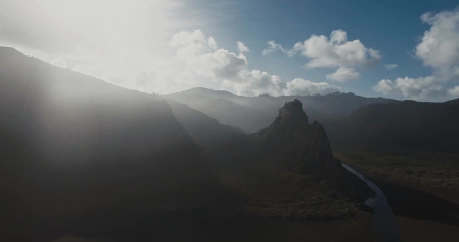 Aerial panorama of peaks and mountains with a ribbon of river and the morning suns reflection