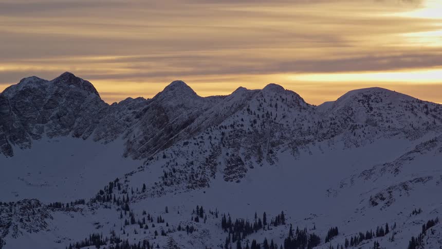 Some white mountains covered in snow and an orange sky