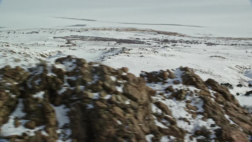 A mountain goat running on a mountain with rocks and snow
