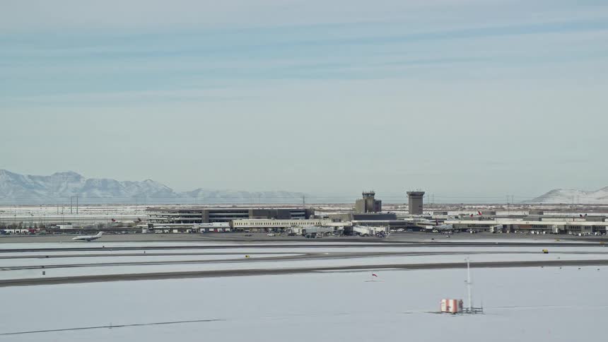 An airport runway with a plane taking off quickly and the environment is covered in snow