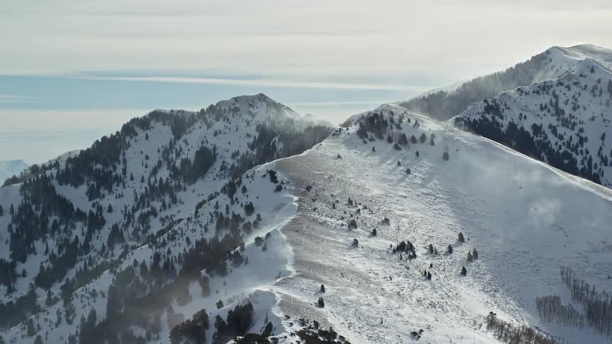Aerial from the top of a snowy mountain during harsh winter