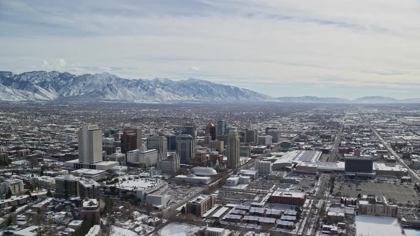 Large city with several buildings during winter with snowcovered mountains in the background
