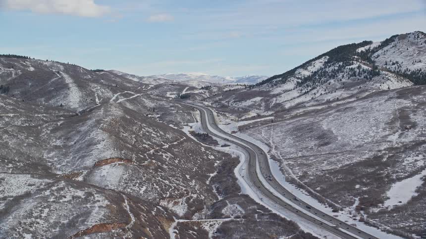 Aerial panorama of a mountain range with a road in the middle with vehicles passing
