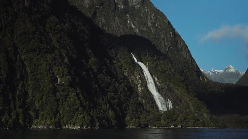 Panorama of mountains with a waterfall in free fall facing a lake