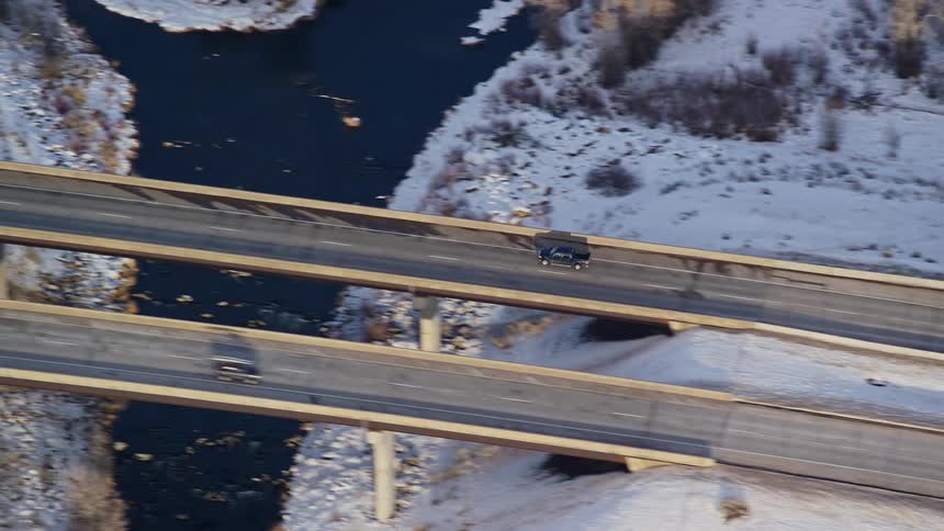 Aerial of a black pickup truck on a snowy road during winter