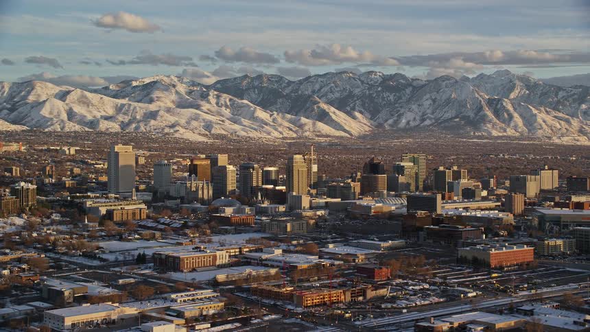 Aerial view of a city with many buildings sitting in front of snow covered mountains