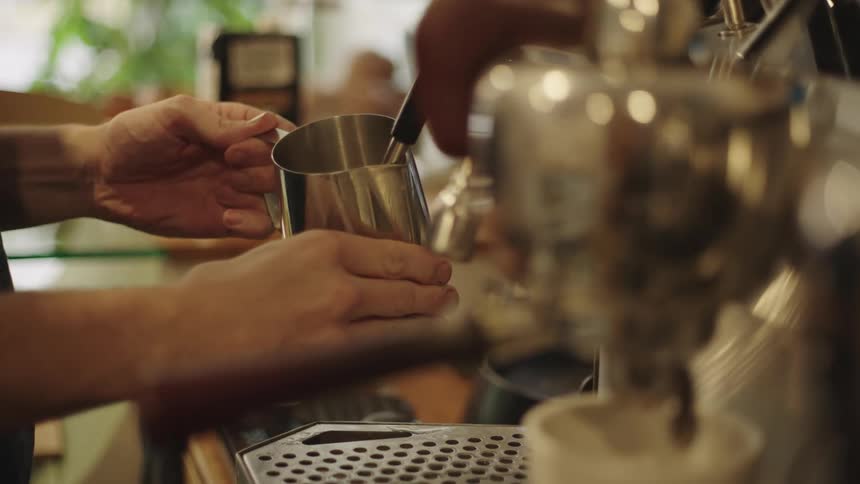 Closeup of a mans hands making a coffee in the machine