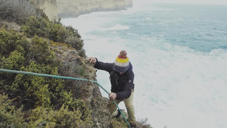A man about to descend the mountain on a rope