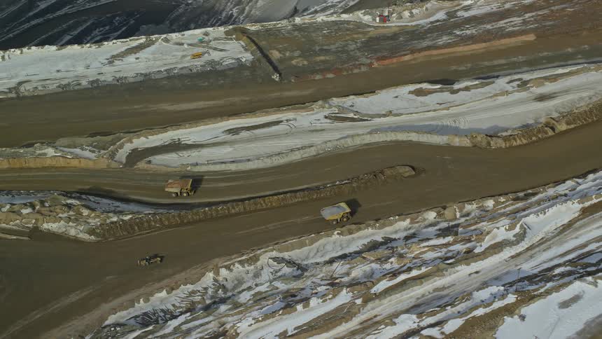 Aerial of mining trucks on a mountain during a snowy day