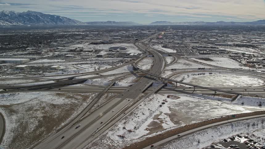 Aerial panorama of roads in the middle of an urban city with snowy ground and mountains on the horizon
