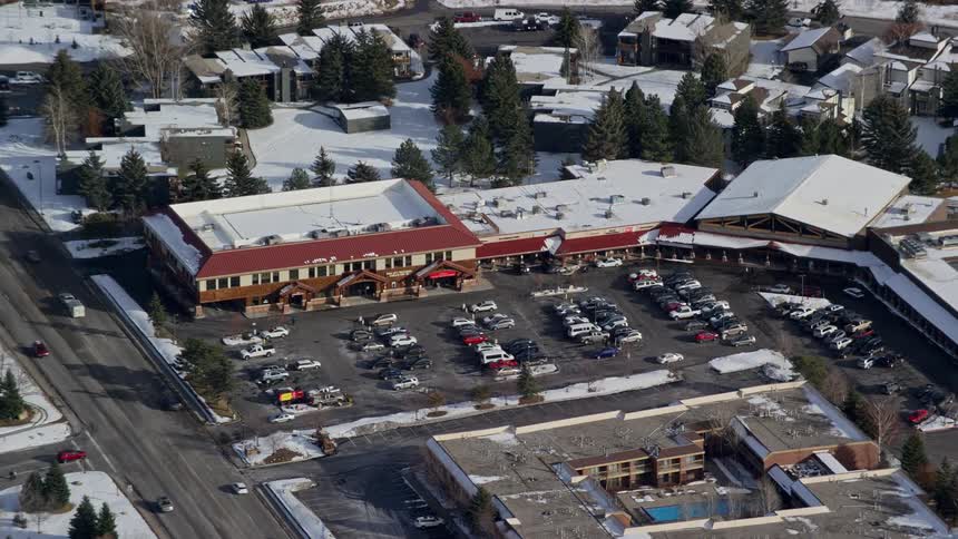 Aerial view of an establishment with parked vehicles in the midst of an urban city covered in snow